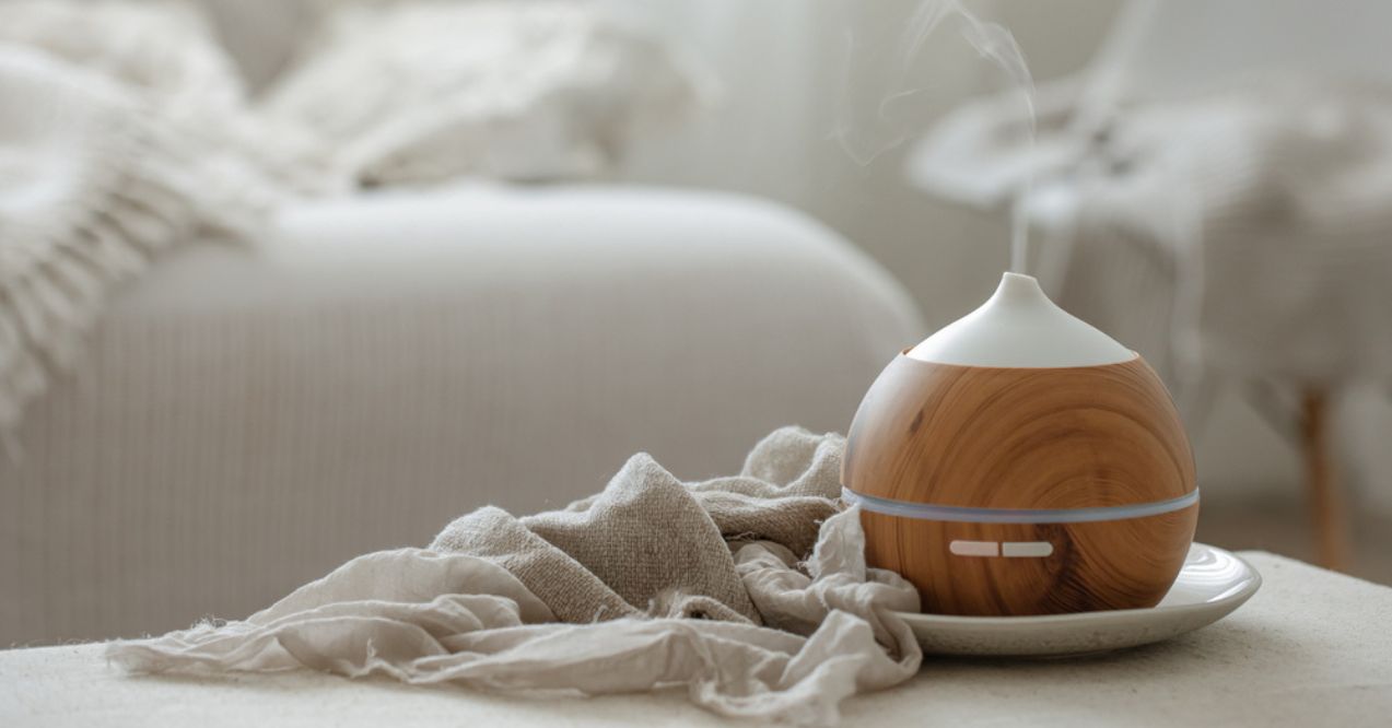 A wooden essential oil diffuser emitting vapor in a cozy bedroom setting