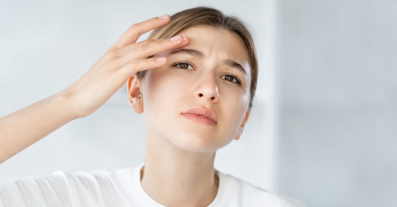 A young woman touching her forehead with a concerned expression