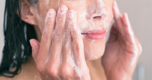 A person washing their face with a foaming cleanser