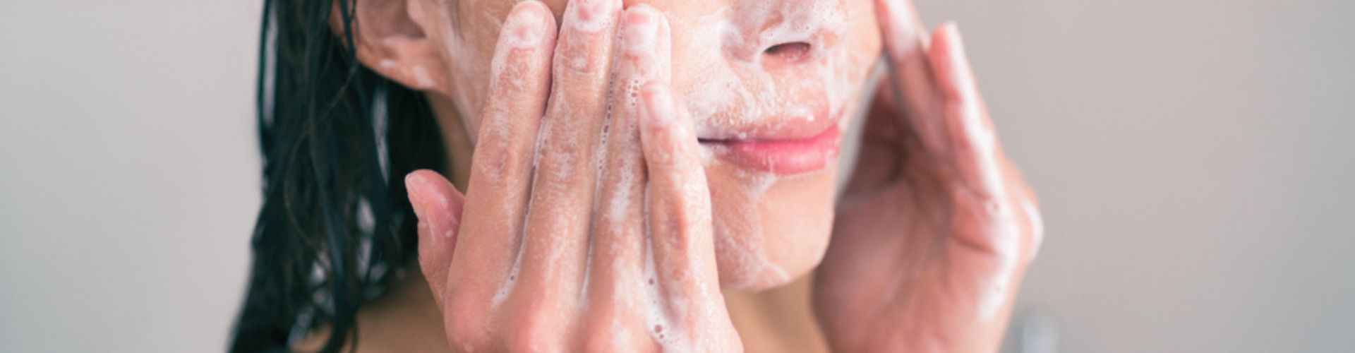 A person washing their face with a foaming cleanser