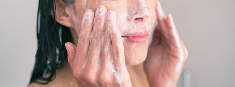 A person washing their face with a foaming cleanser