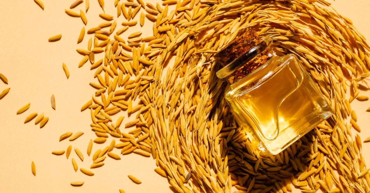 A bottle of rice bran oil surrounded by rice grains 