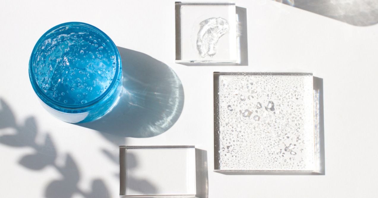 Top view of a blue skincare gel jar and clear glass blocks with shadows