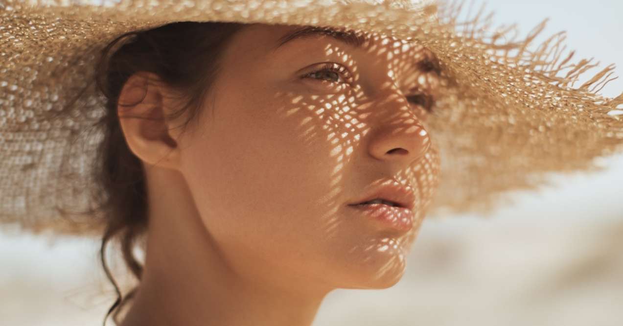 Woman wearing a sun hat with shadows on her face at the beach