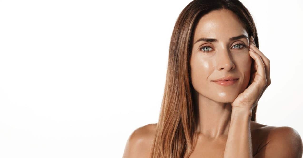 A woman with glowing, healthy skin touching her face