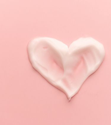 Heart shape skincare cream smear on pink background