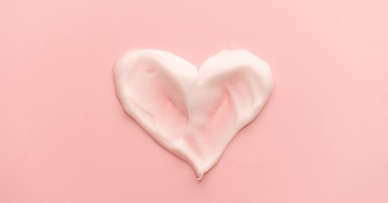 Heart shape skincare cream smear on pink background