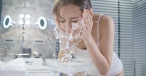 A woman washing her face with splashing water