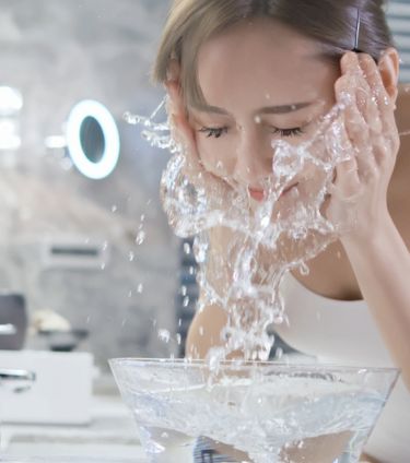 A woman washing her face with splashing water