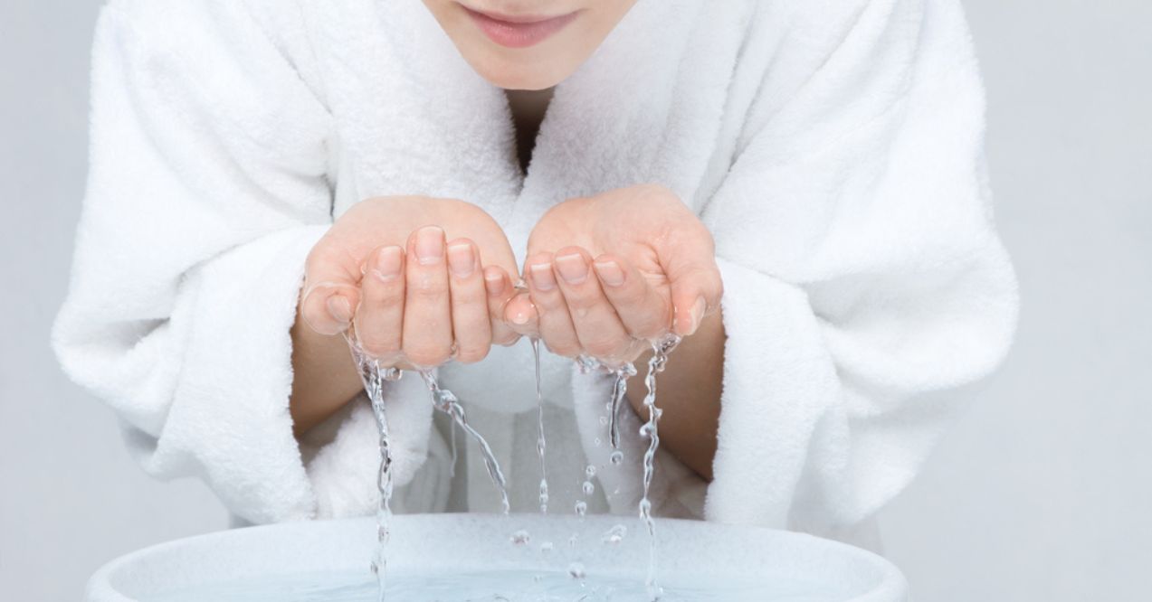 A woman washing her face with cold water