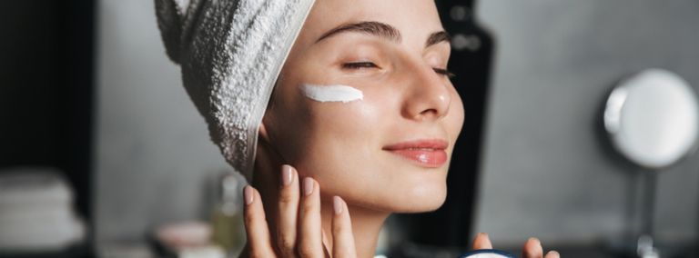 Woman applying face cream with a towel wrapped around her head