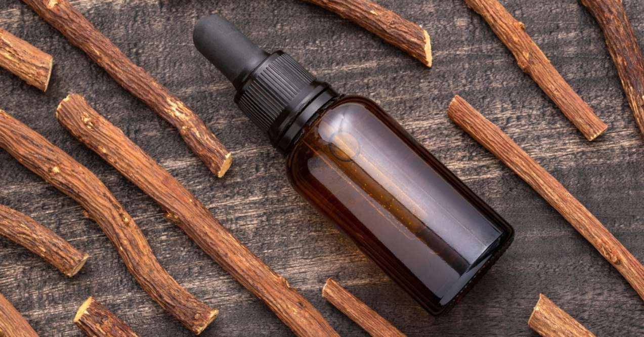 A dark amber dropper bottle surrounded by dried licorice root sticks