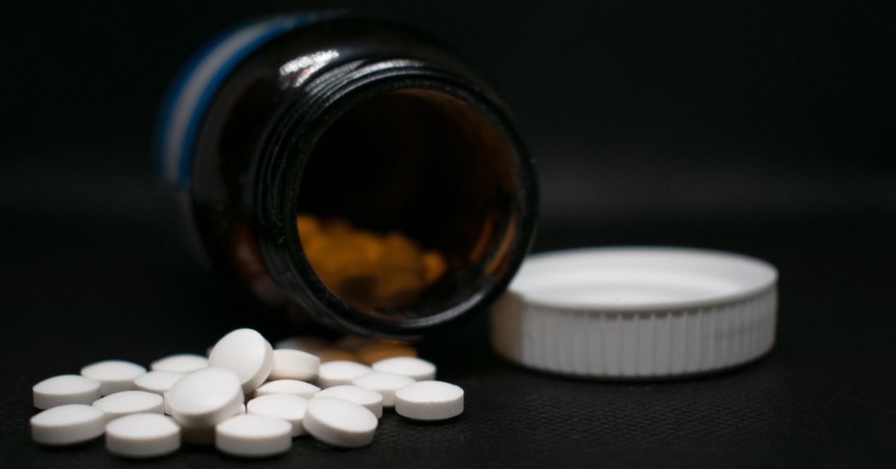 Open medicine bottle with white tablets spilling out