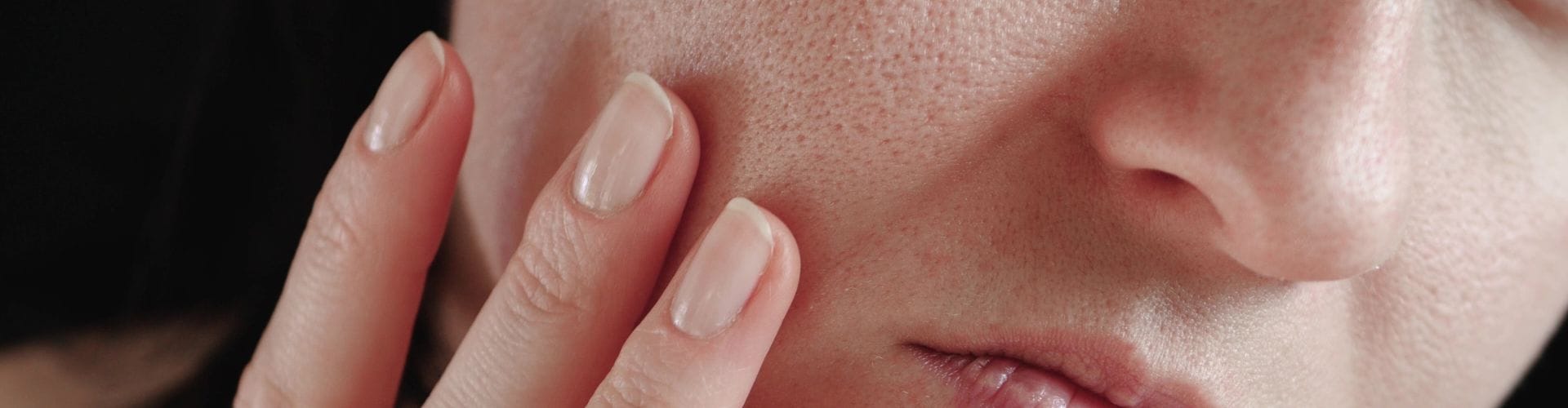 Close-up of a person examining their skin, focusing on visible pores and texture.