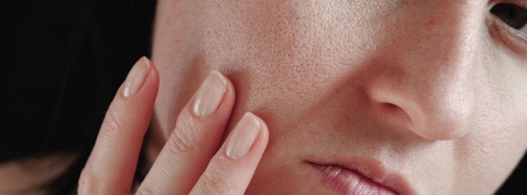 Close-up of a person examining their skin, focusing on visible pores and texture.