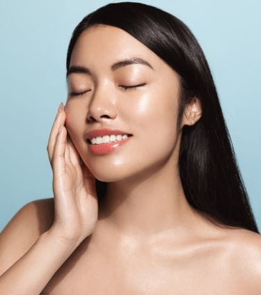 Woman with smooth, glowing skin touching her face, showcasing a radiant complexion.