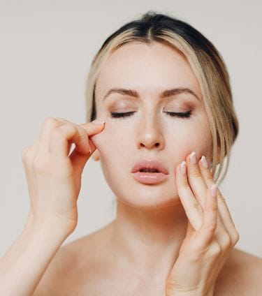 Person performing a facial massage to improve skin elasticity