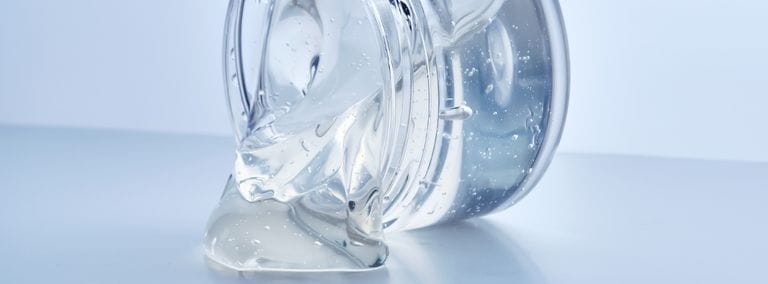 Clear gel in an open jar on a light background