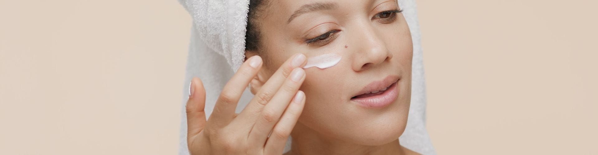 Woman applying moisturizer under her eye, promoting smooth and hydrated skin.