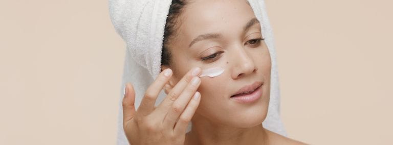 Woman applying moisturizer under her eye, promoting smooth and hydrated skin.