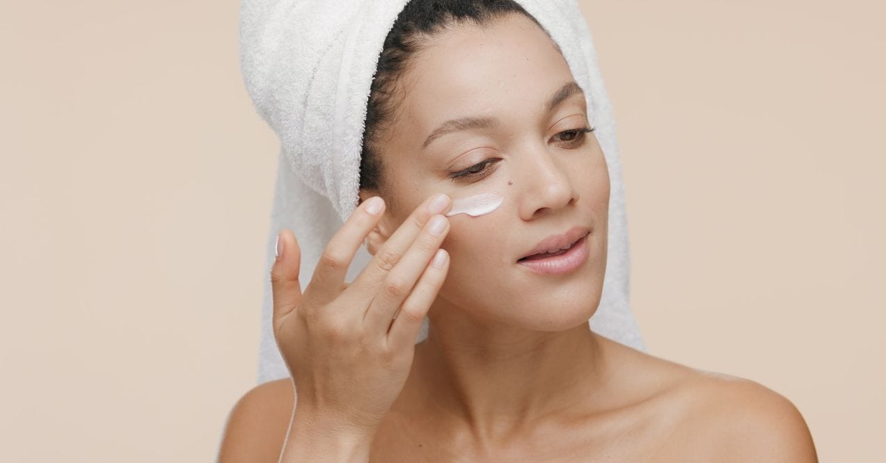 Woman applying moisturizer under her eye, promoting smooth and hydrated skin.