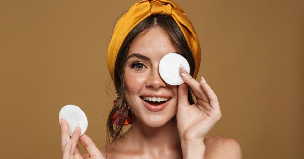 Smiling woman holding cotton pads to her face