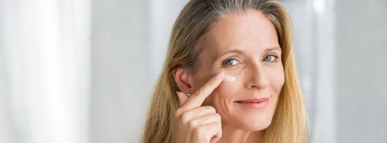 Smiling woman applying eye cream