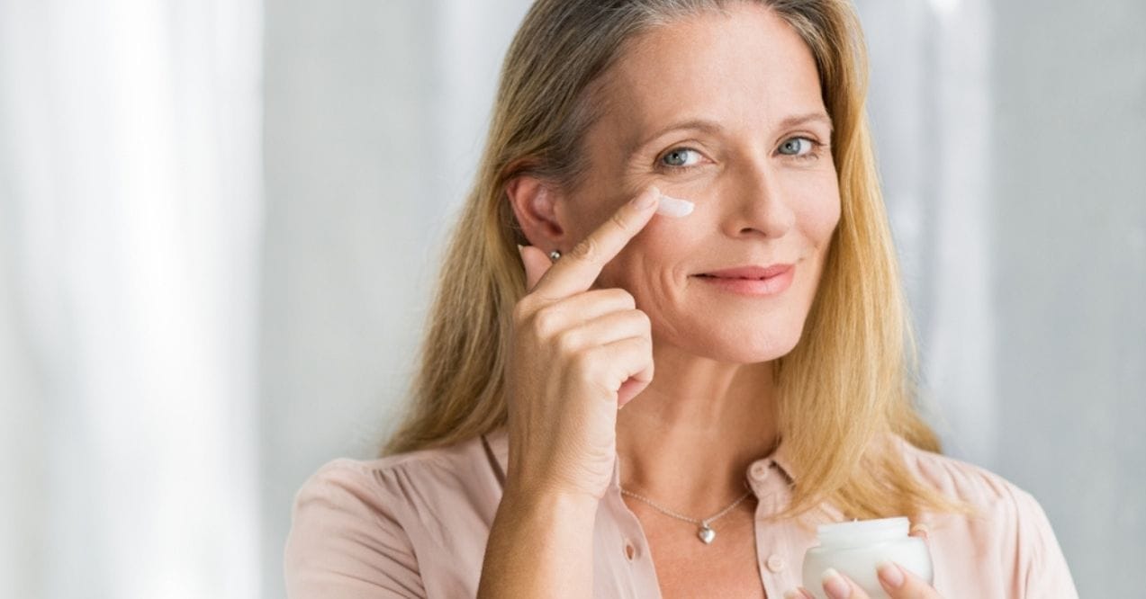 Smiling woman applying eye cream