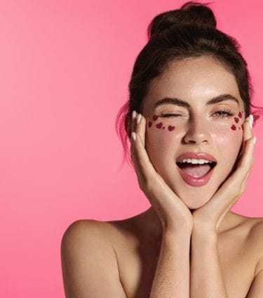 Smiling woman with heart-shaped decorations under her eyes