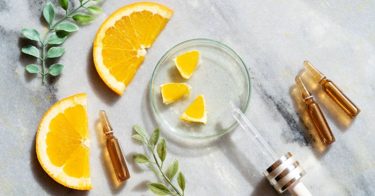 Vitamin C skincare concept with orange slices, ampoules, and a glass dropper