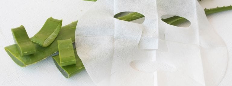 Sheet mask with aloe vera slices on a white background