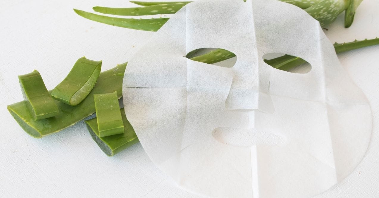 Sheet mask with aloe vera slices on a white background