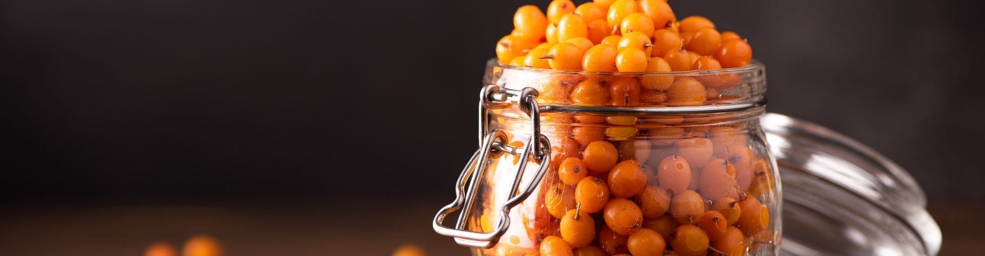 Jar of sea buckthorn berries on a wooden surface