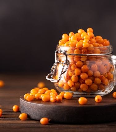 Jar of sea buckthorn berries on a wooden surface