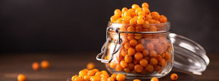 Jar of sea buckthorn berries on a wooden surface