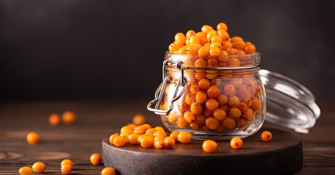 Jar of sea buckthorn berries on a wooden surface