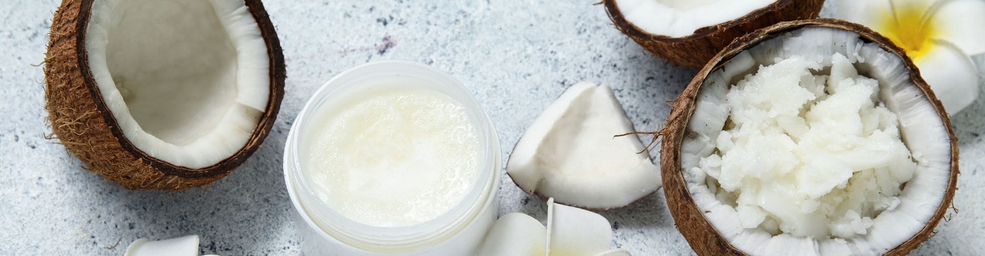 Open coconuts, coconut pieces, white jar of coconut cream, and white flowers arranged