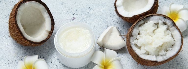 Open coconuts, coconut pieces, white jar of coconut cream, and white flowers arranged