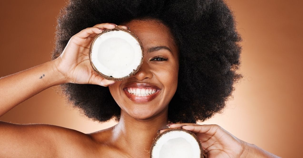 Smiling woman holding two halves of a coconut near her face