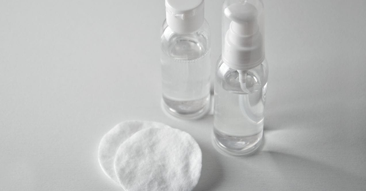 Two clear toner bottles with cotton pads on white background