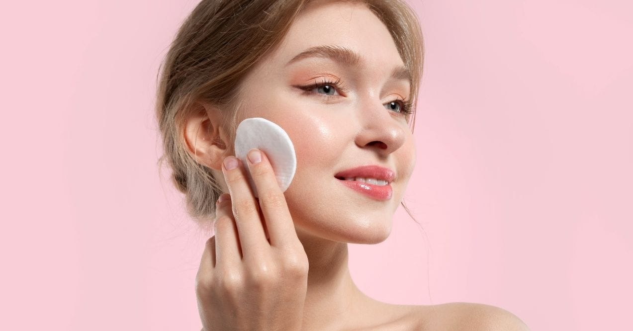 Woman with radiant, glowy skin using a cotton pad on her cheek
