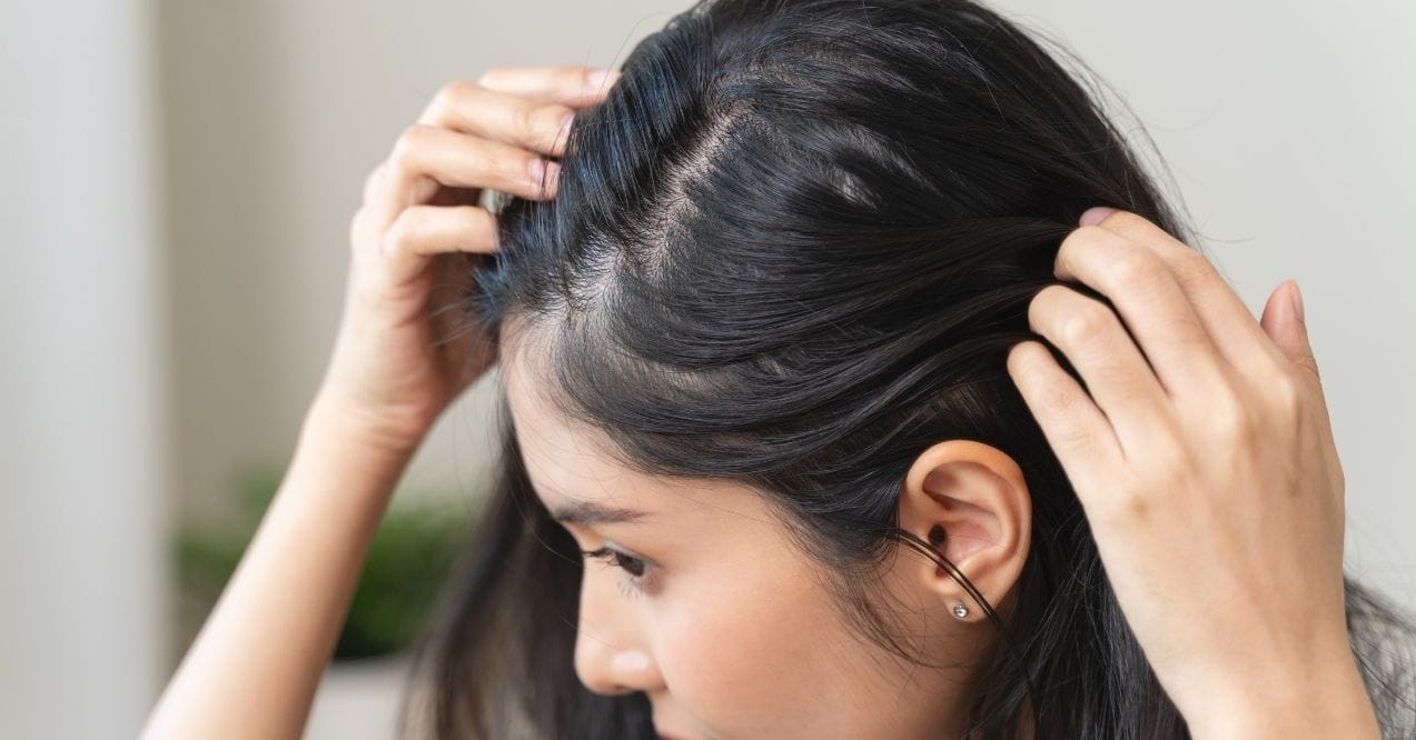 Woman checking thinning hair on scalp in mirror