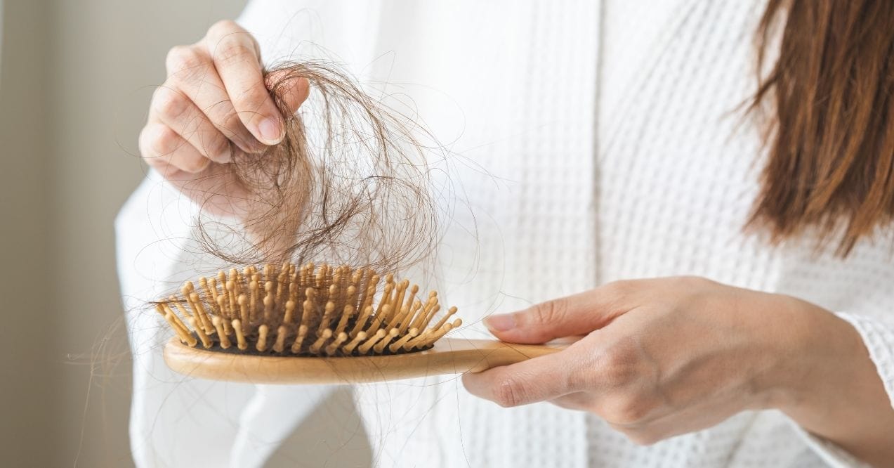 Woman holding hairbrush with fallen hair strands
