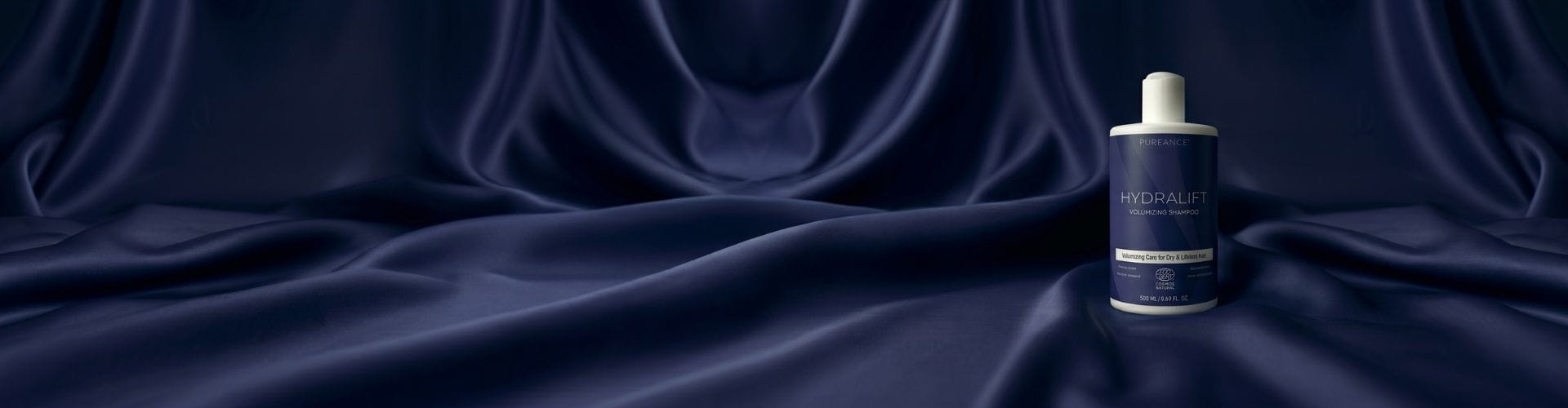 Pureance HydraLift Volumizing Shampoo bottle on dark blue satin fabric